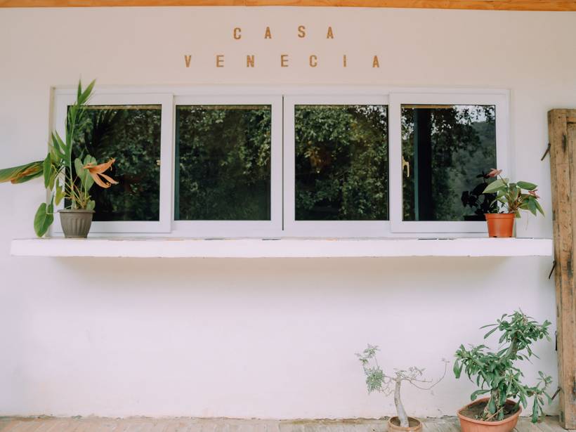 Fachada de Casa Venecia con su letrero y plantas